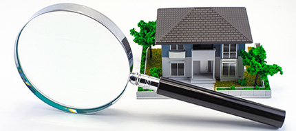 虫メガネとミニチュアの家の模型の写真